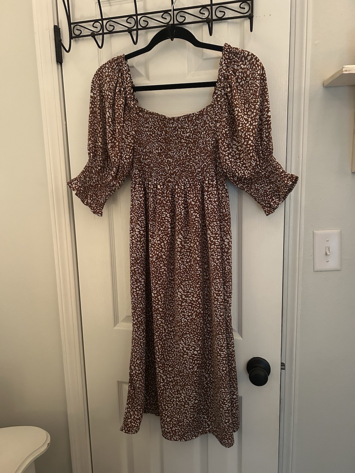 Chic brown dress with floral pattern. Features long sleeves and a smocked bodice