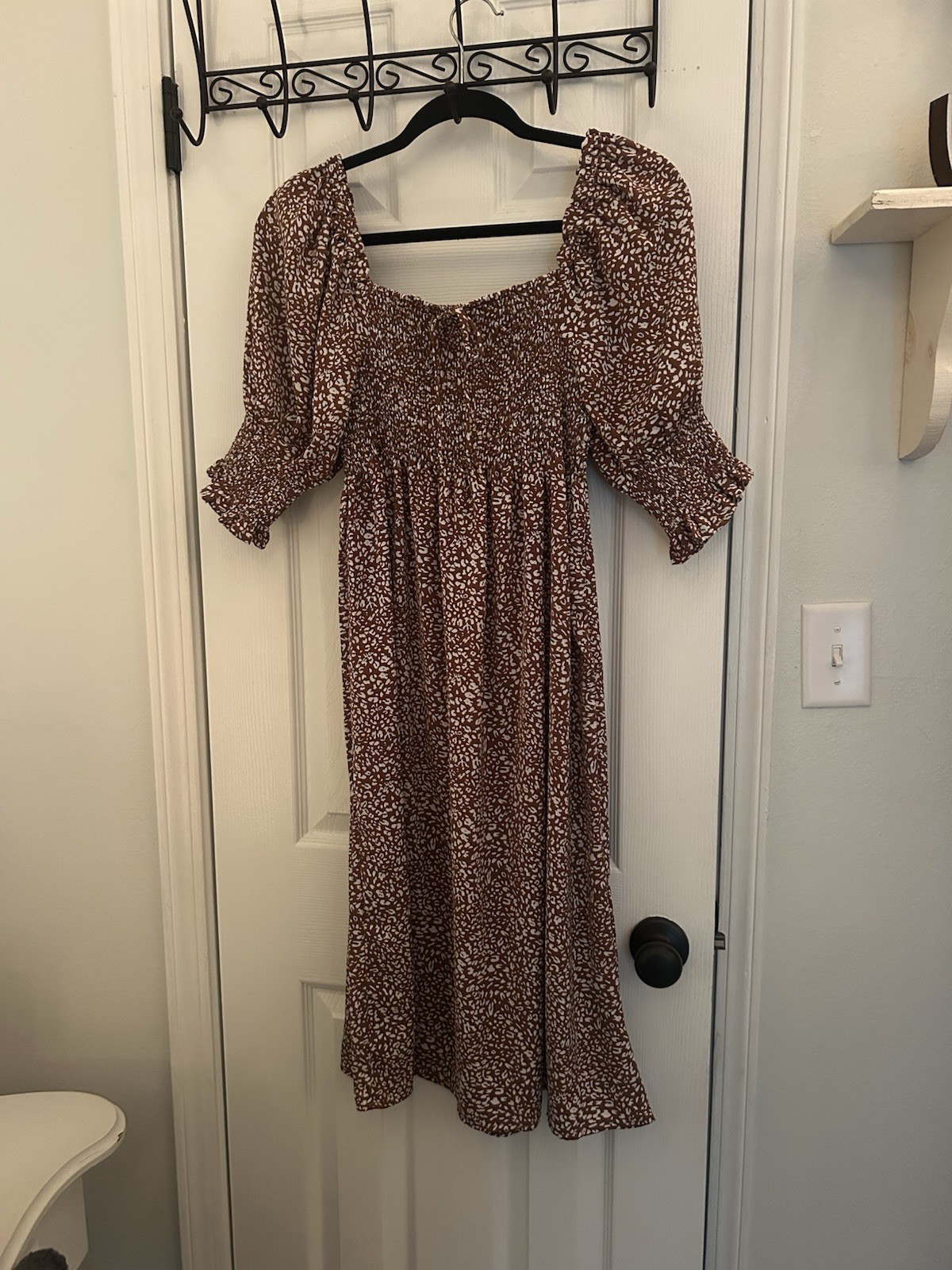 Chic brown dress with floral pattern. Features long sleeves and a smocked bodice