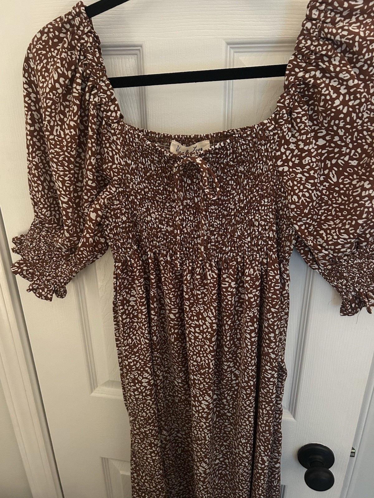 Chic brown dress with floral pattern. Features long sleeves and a smocked bodice