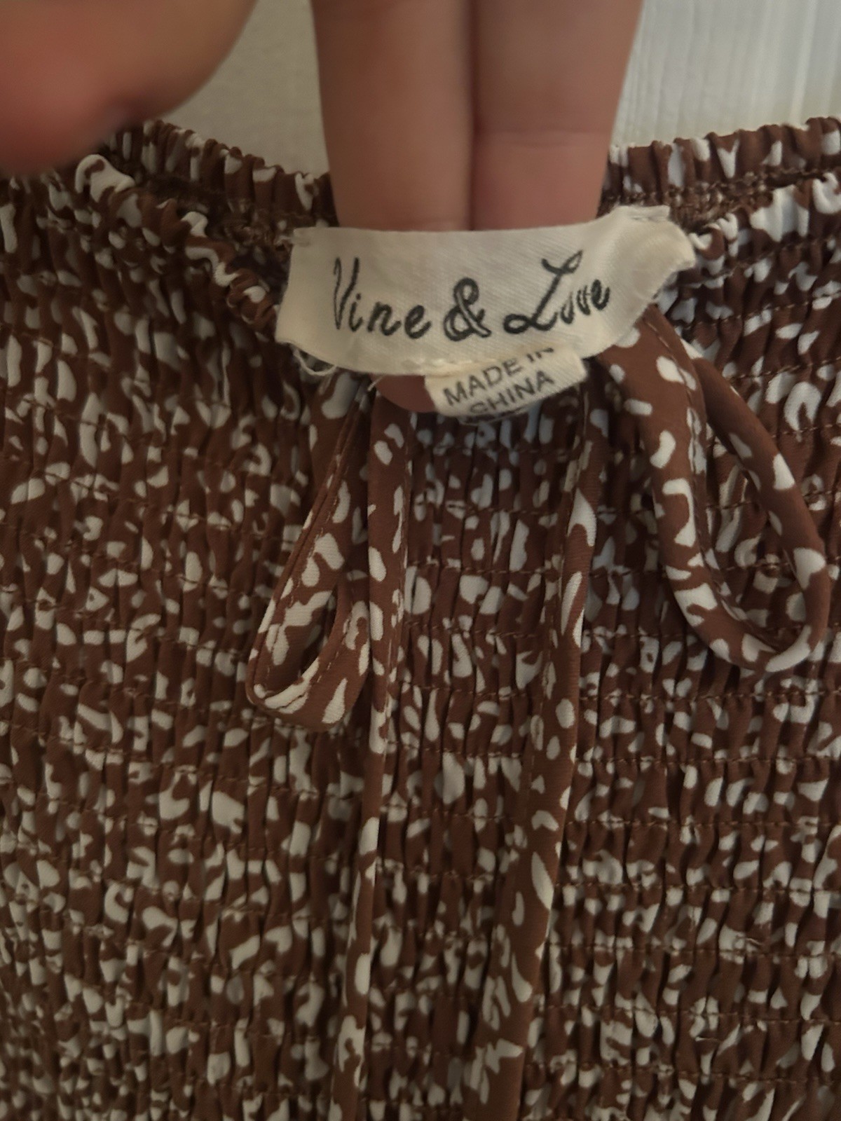 Chic brown dress with floral pattern. Features long sleeves and a smocked bodice