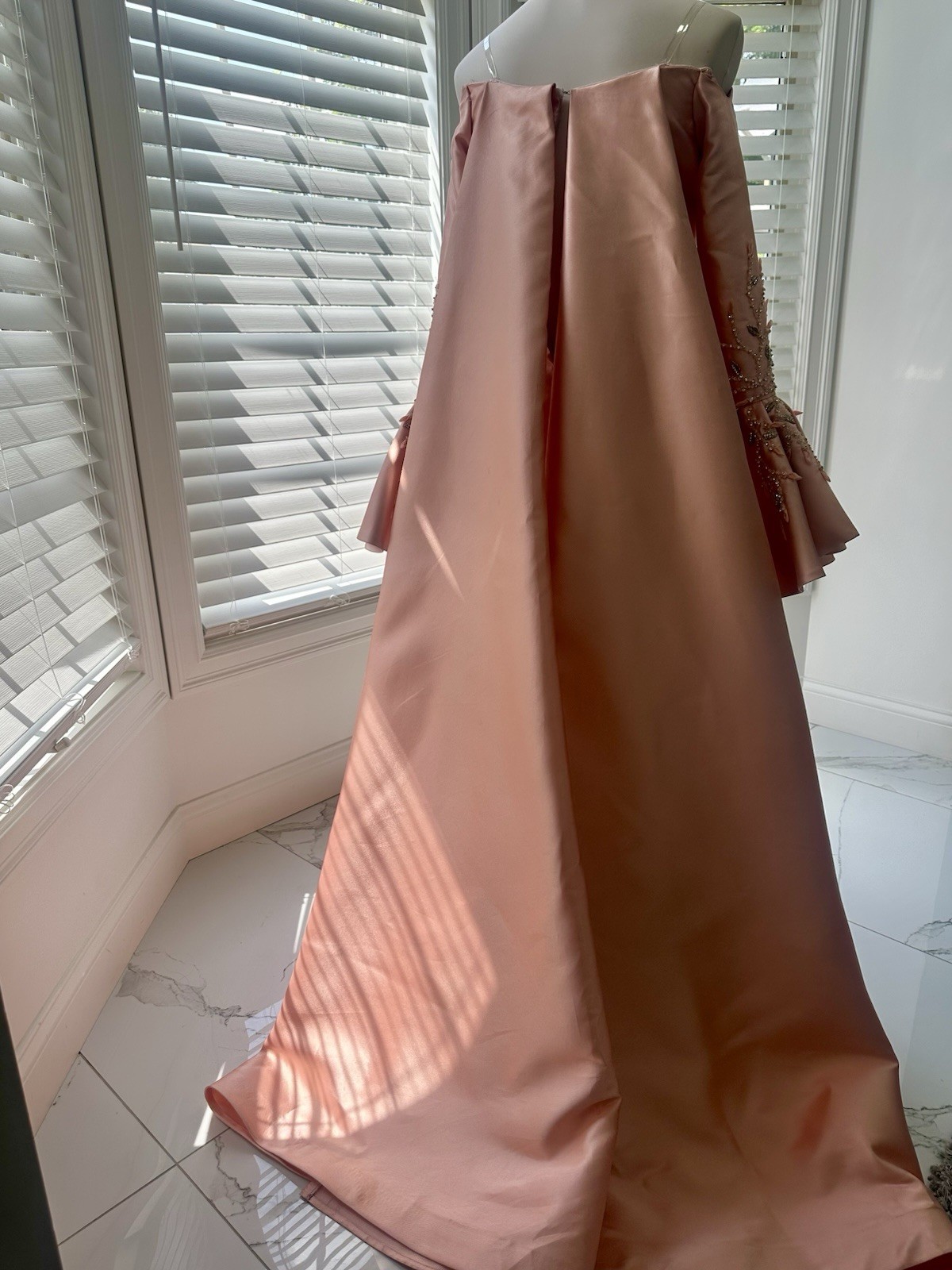 Blush-peach silk gown with floral sleeves, soft drama, and timeless elegance.