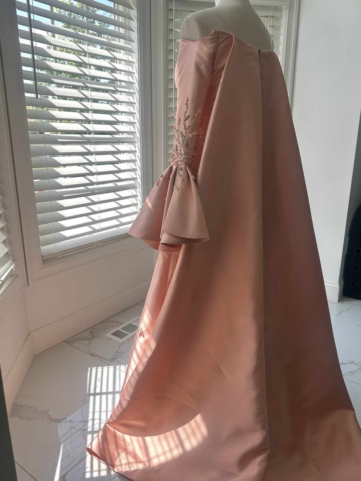 Blush-peach silk gown with floral sleeves, soft drama, and timeless elegance.
