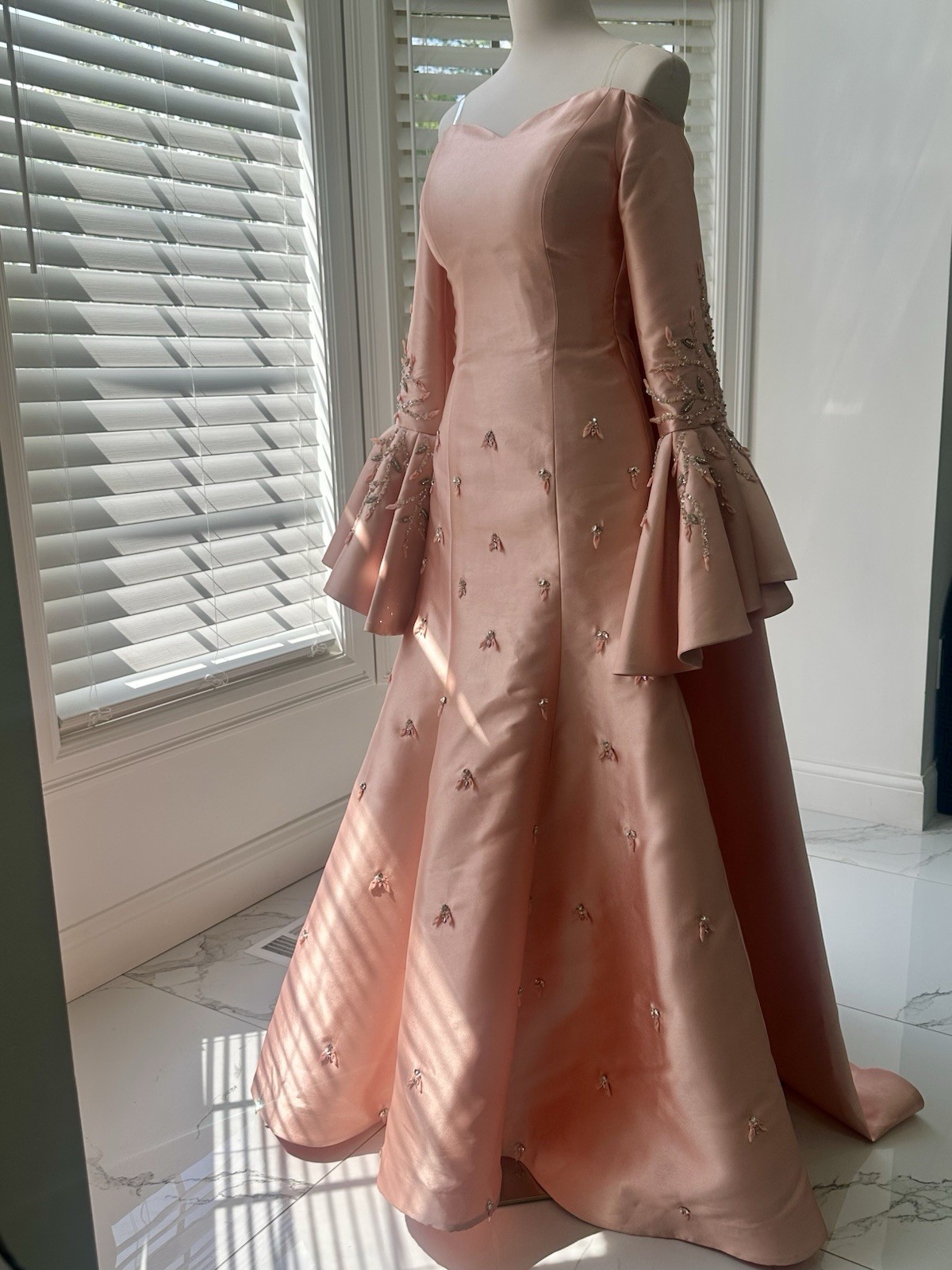 Blush-peach silk gown with floral sleeves, soft drama, and timeless elegance.